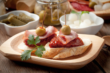 Tapas with sliced sausage, salami, olives and parsley.