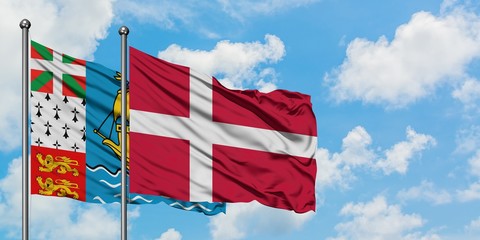 Saint Pierre And Miquelon and Denmark flag waving in the wind against white cloudy blue sky together. Diplomacy concept, international relations.