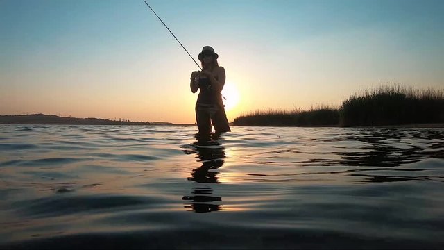 A beautiful girl fishing in Rietvlei Dam, South Africa, with the sun setting in the background