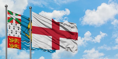 Obraz premium Saint Pierre And Miquelon and England flag waving in the wind against white cloudy blue sky together. Diplomacy concept, international relations.