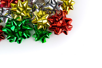 Multi coloured chrome effect Christmas present ribbon bows including silver, red, yellow and green. Set against a white stark background.