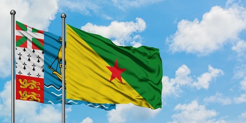 Saint Pierre And Miquelon and French Guiana flag waving in the wind against white cloudy blue sky together. Diplomacy concept, international relations.