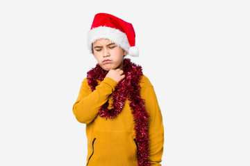 Little boy celebrating christmas day wearing a santa hat isolated suffers pain in throat due a virus or infection.