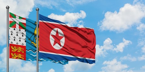 Saint Pierre And Miquelon and North Korea flag waving in the wind against white cloudy blue sky together. Diplomacy concept, international relations.