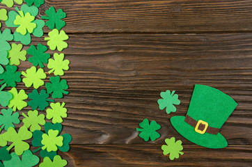 Happy Saint Patrick's mockup of handmade felt hat and shamrock clover leaves on wooden background.