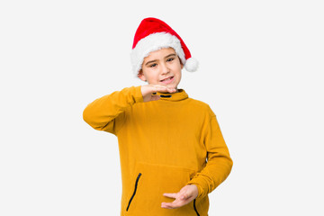 Little boy celebrating christmas day wearing a santa hat isolated holding something with both hands, product presentation.