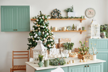 Interior light kitchen with christmas decor and tree. Turquoise-colored kitchen in classic style. Christmas in the kitchen. Bright kitchen in mint and white shades with Christmas. 