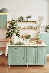 Interior light kitchen with christmas decor and tree. Turquoise-colored kitchen in classic style. Christmas in the kitchen. Bright kitchen in mint and white shades with Christmas. 