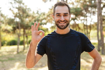 Sports man posing outdoors showing okay gesture.