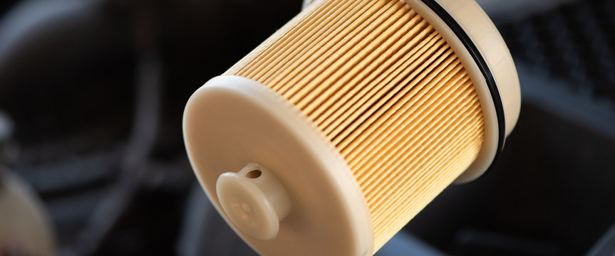 Automotive fuel filter on car engine background