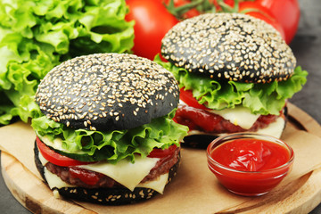 Two black burgers with vegetables and beef meat	