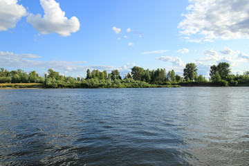 The river, trees and blue sky with some clouds on sunny summer day