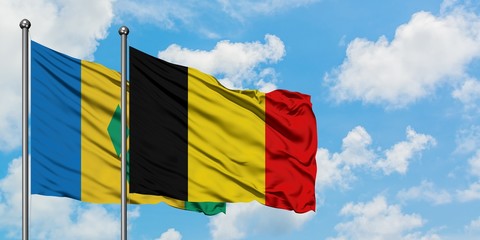 Saint Vincent And The Grenadines and Belgium flag waving in the wind against white cloudy blue sky...