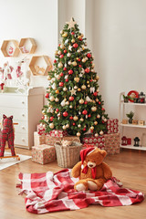 Christmas interior of children's bedroom. New Year's decor and tree in children's playroom. Christmas loft style interior. Сhristmas in the nursery. Soft toy bear on background of Christmas tree