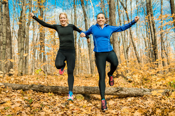 Two Bautiful running woman jogging in autumn nature and jumping