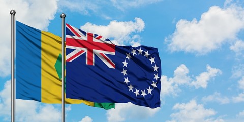Saint Vincent And The Grenadines and Cook Islands flag waving in the wind against white cloudy blue...