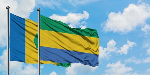 Saint Vincent And The Grenadines and Gabon flag waving in the wind against white cloudy blue sky together. Diplomacy concept, international relations.