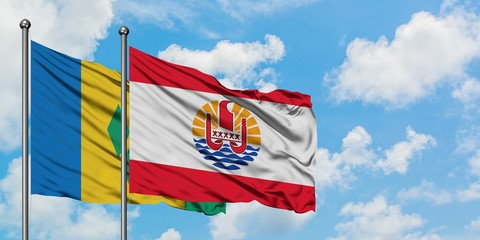 Saint Vincent And The Grenadines and French Polynesia flag waving in the wind against white cloudy...