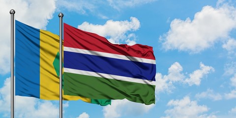 Saint Vincent And The Grenadines and Gambia flag waving in the wind against white cloudy blue sky...