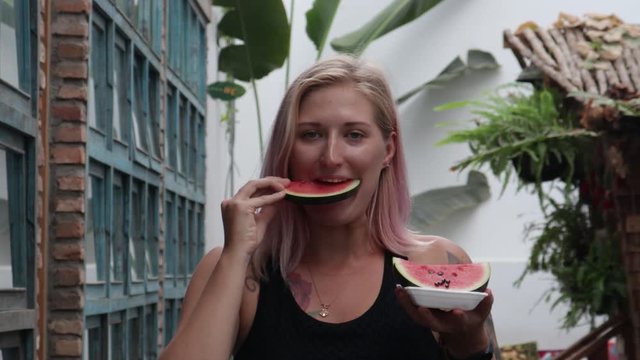 Satisfied girl with tattoos eats fruit.