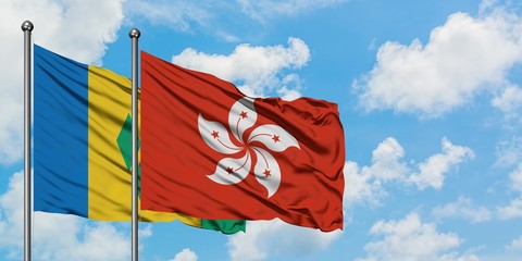 Saint Vincent And The Grenadines and Hong Kong flag waving in the wind against white cloudy blue...