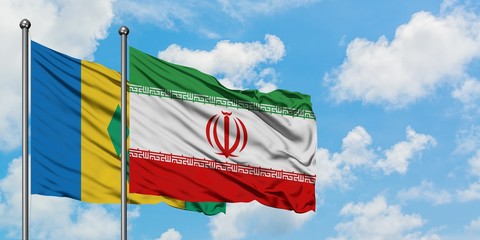Saint Vincent And The Grenadines and Iran flag waving in the wind against white cloudy blue sky...