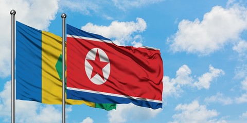 Saint Vincent And The Grenadines and North Korea flag waving in the wind against white cloudy blue sky together. Diplomacy concept, international relations.