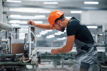 Fototapeta Operator of machine. Industrial worker indoors in factory. Young technician with orange hard hat obraz