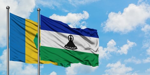 Saint Vincent And The Grenadines and Lesotho flag waving in the wind against white cloudy blue sky together. Diplomacy concept, international relations.