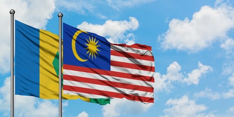Saint Vincent And The Grenadines and Malaysia flag waving in the wind against white cloudy blue sky together. Diplomacy concept, international relations.