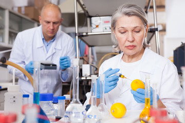 Female lab technician injecting reagent into lemon