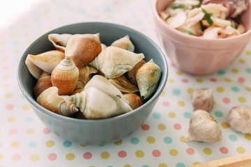 Grilled Laevistrombus Canarium in shells in wooden bowl served with Thai spicy seafood sauce.
