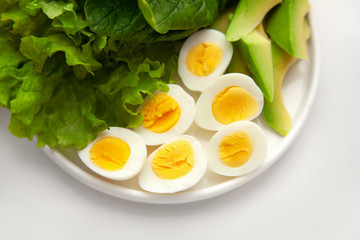 boiled quail eggs, spinach, lettuce, avocado. On a white plate. Close-up