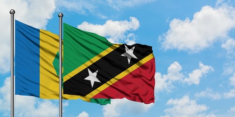 Saint Vincent And The Grenadines and Saint Kitts And Nevis flag waving in the wind against white cloudy blue sky together. Diplomacy concept, international relations.