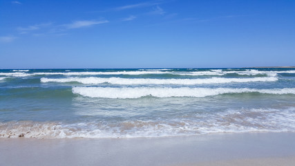 The sea is agitated. Beautiful waves on a sandy beach. Sea, waves, and blue sky.