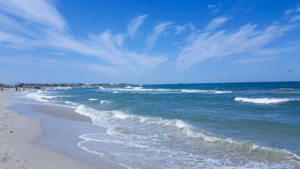 Fototapeta na wymiar The sea is agitated. Beautiful waves on a sandy beach. Sea, waves, and blue sky.