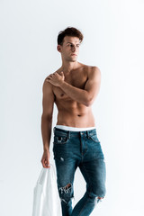 sexy man holding shirt and standing isolated on white