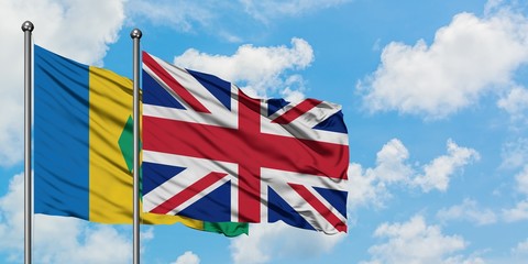 Saint Vincent And The Grenadines and United Kingdom flag waving in the wind against white cloudy...