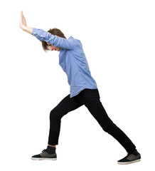 Determined teenage guy making effort as pushing an heavy invisible object isolated on white...