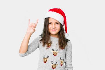 Little girl celebrating christmas day showing a horns gesture as a revolution concept.