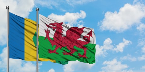 Saint Vincent And The Grenadines and Wales flag waving in the wind against white cloudy blue sky...