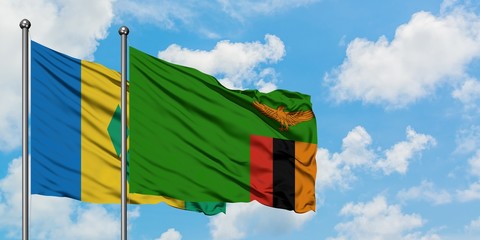 Saint Vincent And The Grenadines and Zambia flag waving in the wind against white cloudy blue sky...