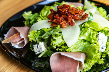 Salad with prosciutto and pear, blue cheese and sun-dried tomatoes