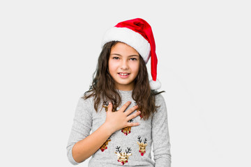 Little girl celebrating christmas day laughs out loudly keeping hand on chest.