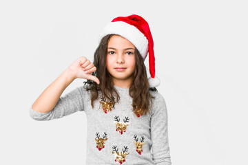 Little girl celebrating christmas day showing a dislike gesture, thumbs down. Disagreement concept.