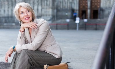 Elegant adult woman is posing sitting in time walking