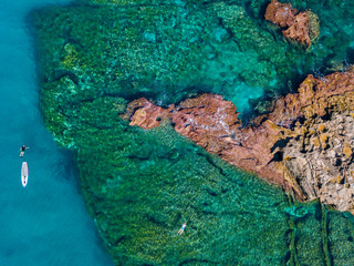 Aerial view of a paddle board in the water floating on a transparent sea, snorkeling. Bathers at sea. Tropea, Calabria, Italy. Diving relaxation and summer vacations. Italian coasts, beaches and rocks