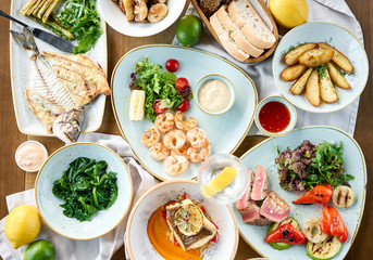 Plates seafood BBQ with garnish. Variety of dishes on the table. Restaurant menu.