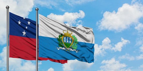 Samoa and San Marino flag waving in the wind against white cloudy blue sky together. Diplomacy...