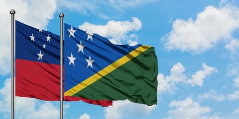 Samoa and Solomon Islands flag waving in the wind against white cloudy blue sky together. Diplomacy...